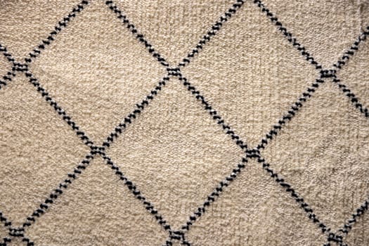 Beige fabric texture. Close-up of a light brown carpet textile background with a pattern of squares. Macro photograph. Beautiful bright backdrop with space.