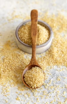 Wooden scoop and bowl with Dry uncooked bulgur wheat grain close up. Vegetarian and Vegan, Mediterranean and Middle Eastern cuisine. Healthy food