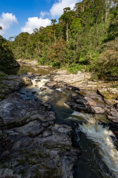 Madagascar mountain river in tropical forest on the hills. Sunny day. Ranomafana national park. Madagascar wilderness landscape