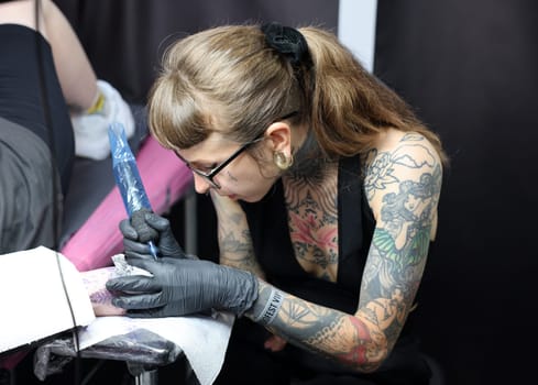 Krakow, Poland -  June 12, 2022: Unidentified  participant at 15th Tattoofest Convention in Cracow. Tattoo artist at work.