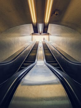 Lone man climbing out on a subway escalator. Symmetrical underground moving staircase