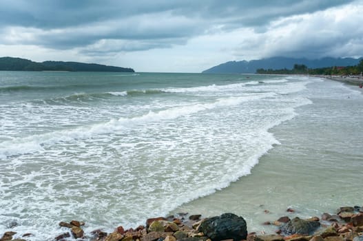 Rising tide with beachgoers on a cloudy evening