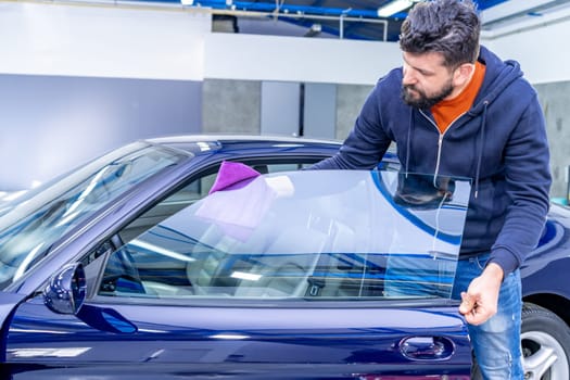 manual cleaning of car windows with a microfiber towel in the garage. High quality photo