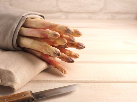 Tasty organic purple asparagus on a rustic wooden kitchen table, close up, healthy food