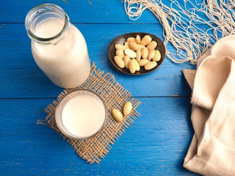 Glass of a tasty organic almond drink on a blue wooden table, healthy food or drink concept