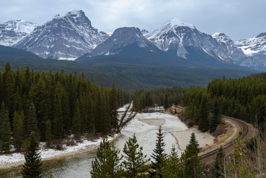 Scenic Morant's Curve of Bow River and curved railroad track with snow-covered Mount temple background in Banff National Park, Alberta, Canada