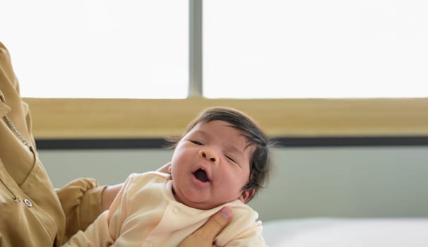 Adorable newborn baby girl yawn sleepy on mom hands. Healthy newborn baby concept