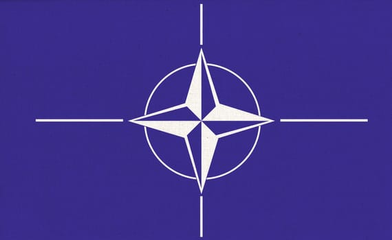 NATO (North Atlantic Treaty Organization) flag. NATO is international military alliance that constitutes system of collective security. NATO flag on fabric surface