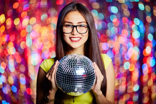 Posh girl with disco ball looking at camera in club