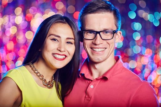 Cheerful couple looking at camera at party in nightclub