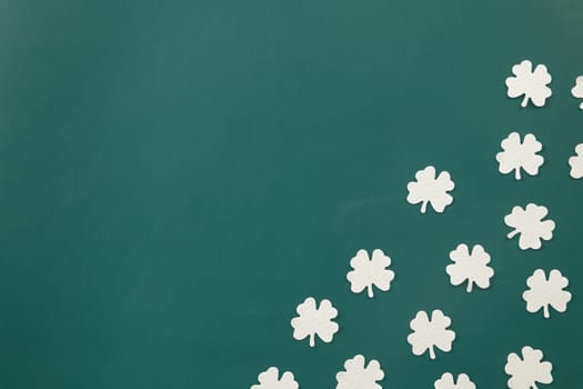 Happy St Patricks Day decoration background. above top view of paper clover leaves festive decor, shamrocks leaves holiday symbol with copy space on colour background, Banner greeting card concept