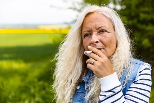 Portrait from a Lady smoking outdoor a cigarette.
