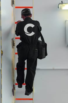 Civitavecchia, Italy - February 18, 2025: A Costa Cruises worker climbs an orange ladder inside a ship. The detailed image captures the professionalism and commitment of the cruise line staff.