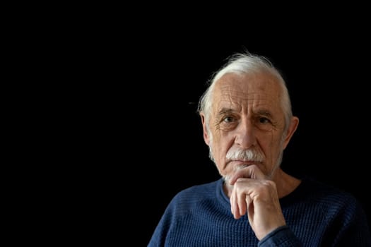 Beautiful gray hair old man wirh wrinkled face is posing on black background looking at the camera.