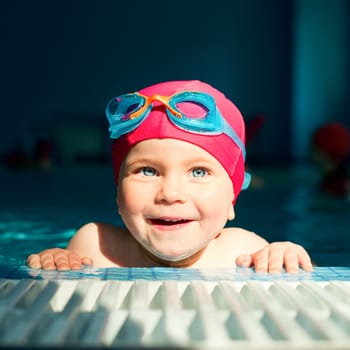 Happy little girl looking out from swimming pool