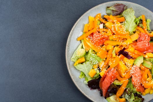 Fresh salad with salmon, mango, sesame and vegetables. Salad and chopsticks
