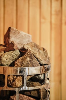 Closeup view of rocks and stones in cage in sauna heater (photo with shallow depth of field)
