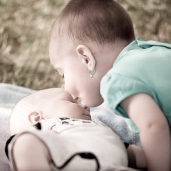 Bay girl giving a kiss to her new born baby brother