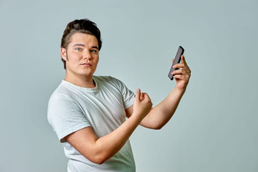 A man looks at the phone screen on a gray background. High quality photo