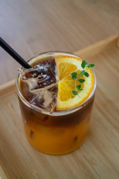 Iced black orange coffee on wooden table, stock photo