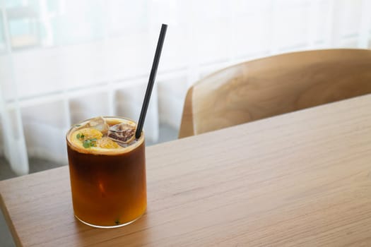 Iced black orange coffee on wooden table, stock photo