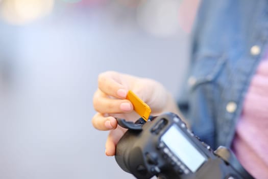 Close up of a photographer hand insterting sd card on camera in the street