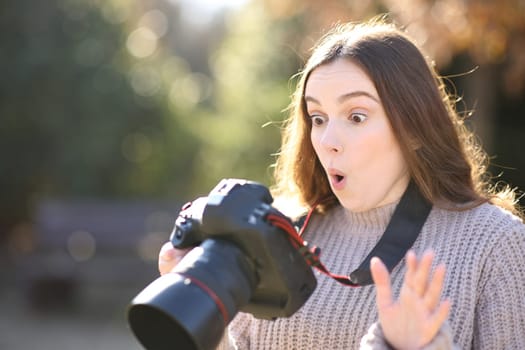 Amazed photographer checking photos on camera in winter