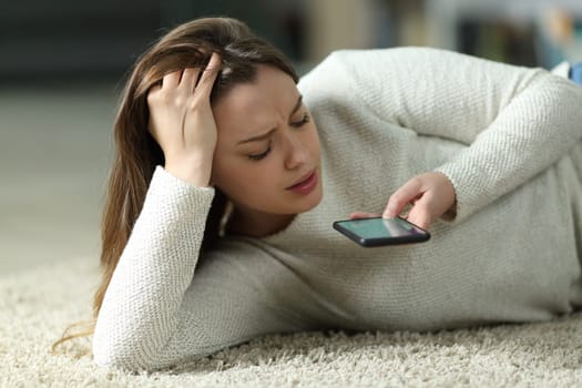 Worried teen lying on the floor dictating message on phone