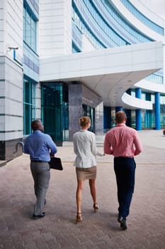 Backs of business group interacting while approaching office building