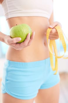 Slim female holding measuring tape and green apple
