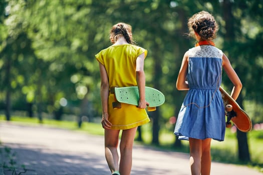 Backs of girls carrying skateboards
