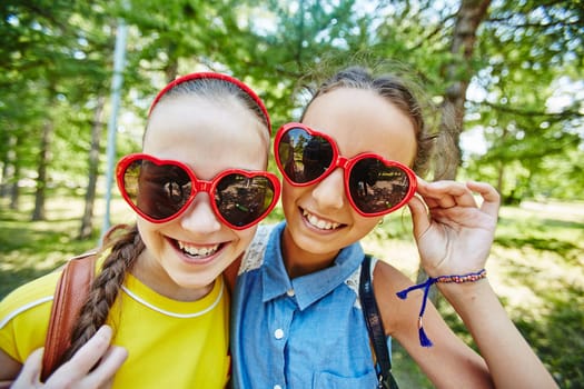 Friendly girls in sunglasses looking at camera outdoors
