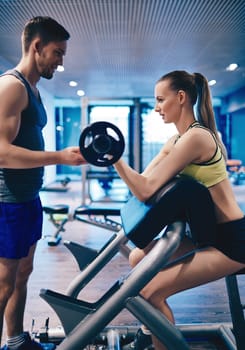 Active female weightlifting and trainer helping her