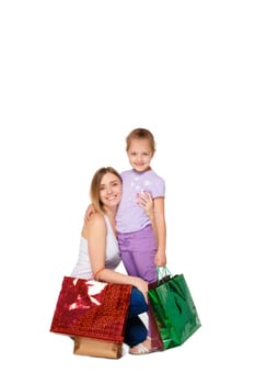 Happy  mother and daughter with shopping bags standing at studio, isolated on white background.  daughter hugging her mother