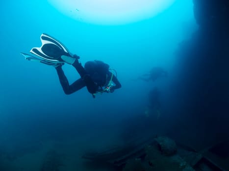scuba diver diving a wreck in deep blue sea, the image has a moody and mysterious atmosphere