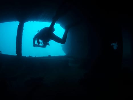 unrecognizable scuba diver diving in the dark water of a shipwreck, the image has a moody and mysterious atmosphere, as the man is the only visible figure in the scene