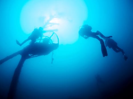 group of divers scuba diving in a wreck at ocean, the water is blue and the sun is shining brightly