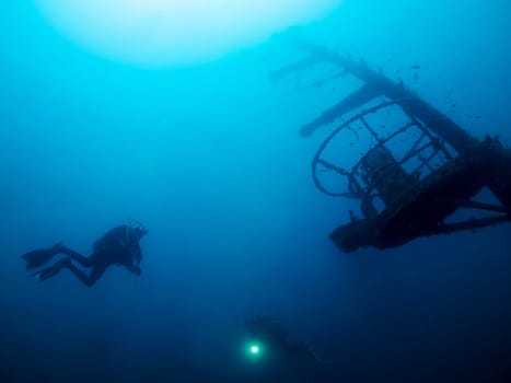 scuba diver swimming near of wreck into the ocean, the image has a moody and mysterious atmosphere