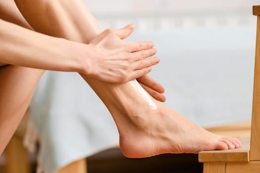 Closeup view of female arms applying cream on foot