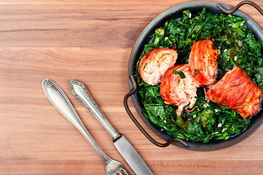 Baked chicken roll with fried spinach leaves. Space for text