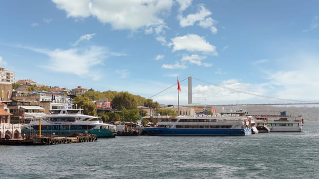 View of the European coast of the Bosporus strait in Besiktas district with docked ferry boats, and Bosphorus Bridge in the far end, Istanbul, Turkey