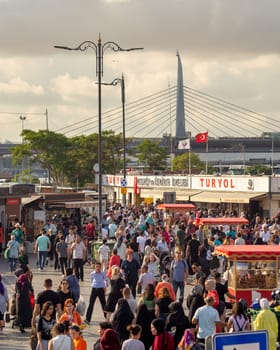 Istanbul, Turkey - August 30, 2022: Crowds of local citizens at Eminonu Plaza during the Victory Day holiday with background of Istanbul city view including Golden Horn Metro Bridge