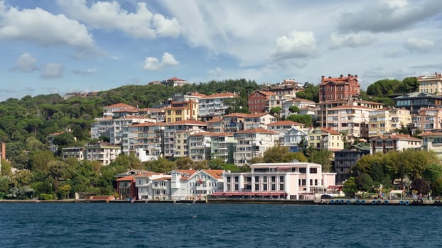 Istanbul, Turkey - August 29 2022: View from Bosphorus strait of the green mountains of the Asian side, with traditional houses and dense trees in a summer day