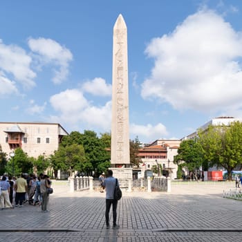 Istanbul, Turkey - August 30 2022: Tourists visiting the Obelisk of Theodosius, ancient Egyptian obelisk of Pharaoh Thutmose III re-erected in the Hippodrome of Constantinople, or Sultanahmet Square