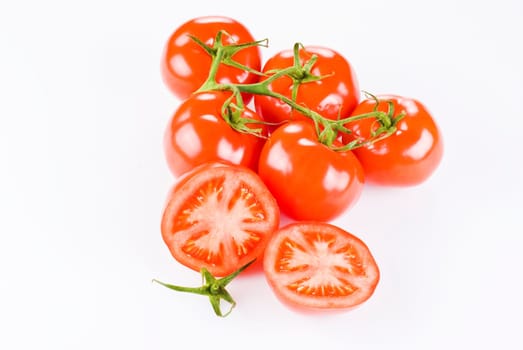 Bunch of tomatoes with two halves over white background