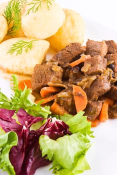 Meal of stewed beef steak with roast potatoes and fresh salad