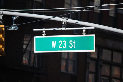 Green big West 23rd Street sign hanging on a arch pole in the streets of midtown Manhattan