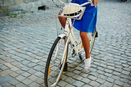 Young female in blue skirt riding bicycle in urban environment