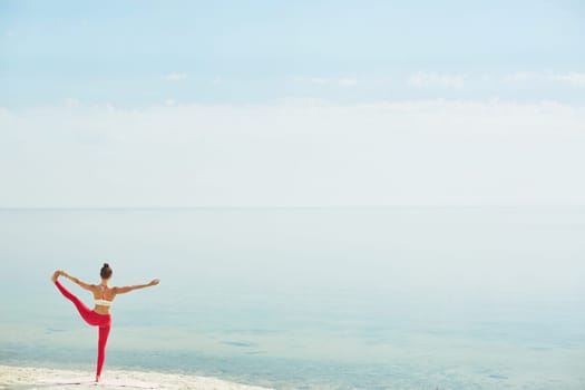 Back view of fit female stretching her leg while standing on the beach