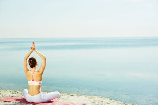 Young woman doing yoga exercise on sandy beach
